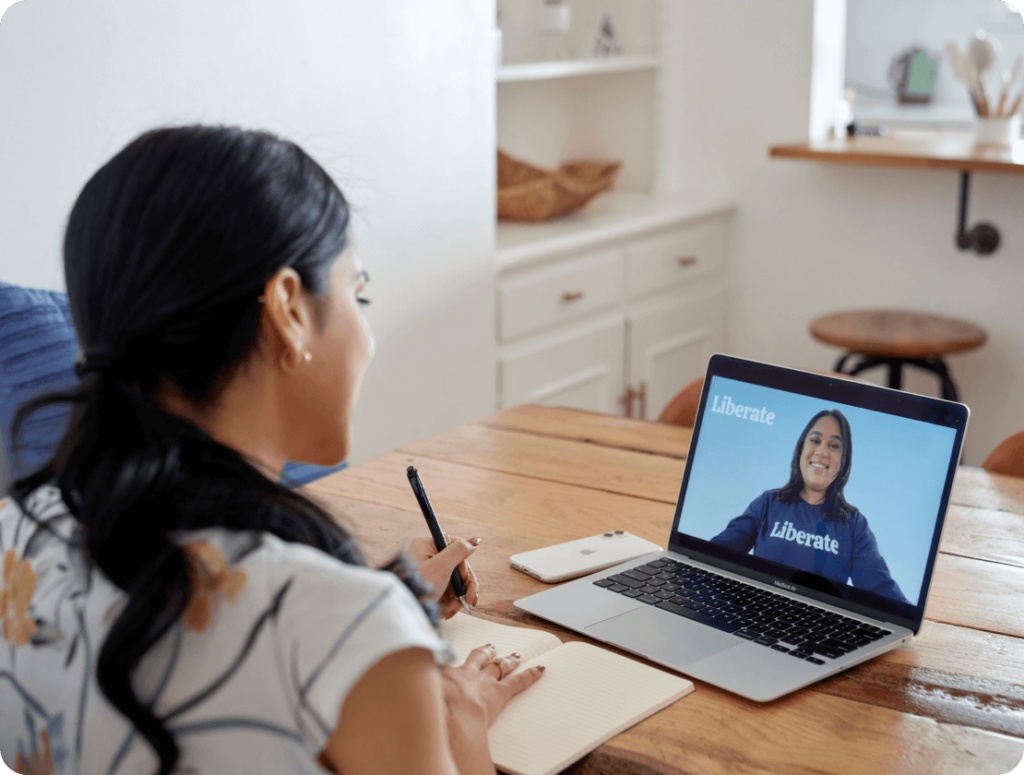 woman journaling in front of laptop